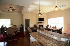 a kitchen and living room are shown in this image, with the ceiling fan turned on