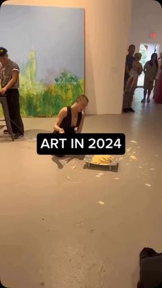 a man sitting on the ground in front of a painting with words that read art in 202