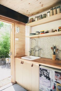 a kitchen with wooden cabinets and open glass doors that lead to an outside patio area