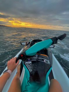 a person riding on the back of a boat in the middle of the ocean at sunset