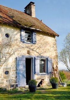 an old stone house with blue shutters on the front and side windows is shown