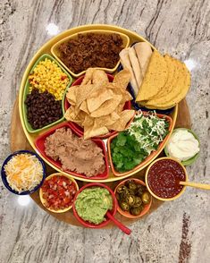 a platter filled with different types of salsa and tortilla chips on a table