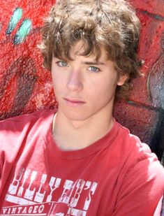 a young man standing in front of a wall with graffiti on it's walls