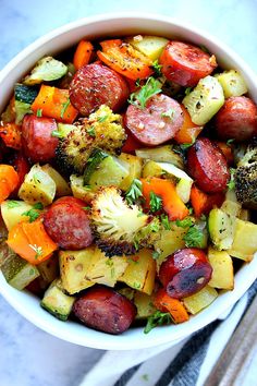 a white bowl filled with potatoes, carrots and broccoli on top of a table