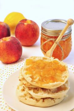 a stack of pancakes on top of a white plate next to some apples and oranges