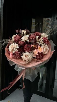 a woman holding a bouquet of flowers in front of a door with her hand wrapped around it