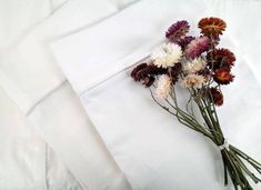 a bunch of dried flowers sitting on top of a white bed sheet and pillowcase