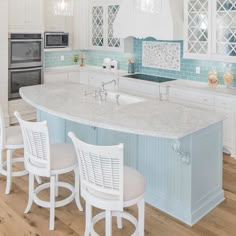 a large kitchen with white cabinets and blue tile backsplashes, an island countertop and four stools