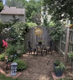 a small backyard with a table and chairs in the middle, surrounded by plants and trees