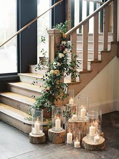 candles and flowers are arranged on wooden logs in front of the stairs at this wedding venue