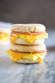 a stack of breakfast sandwiches sitting on top of a marble countertop with eggs, ham and cheese