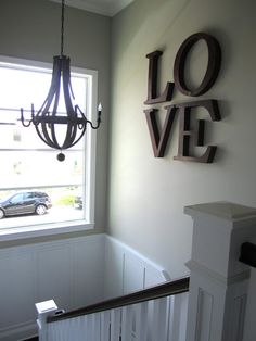 a stairway leading up to a window with the word love on it and a chandelier hanging above