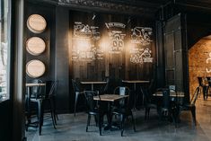 an empty restaurant with black chairs and chalk writing on the walls, along with wooden tables