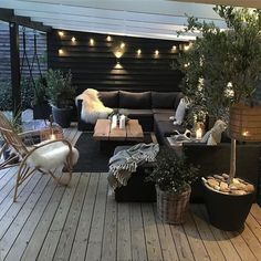 an outdoor living area with couches, tables and lights