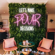 two chairs and a table in front of a green wall that says let's make pour