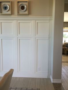 a living room with white paneling and two pictures on the wall