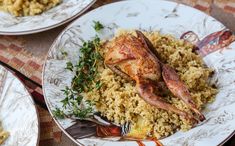 two white plates with food on them, one has chicken and the other has rice