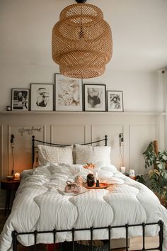 a bed with white sheets and pillows in a bedroom next to pictures on the wall