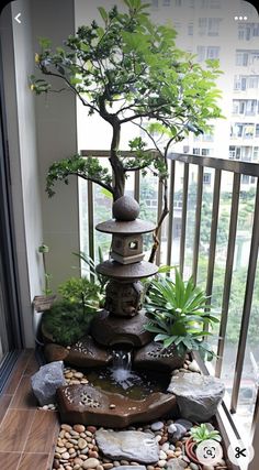 a bonsai tree in the corner of a balcony with rocks and stones around it