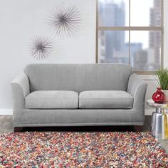 a living room scene with focus on the couch and rug in front of the window