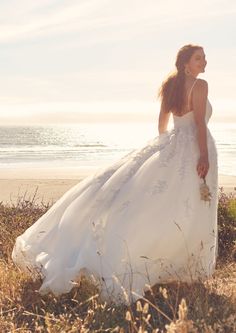 a woman in a wedding dress standing on the beach