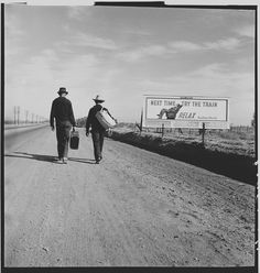 two men walking down the road with luggage in their hands and a sign that says west trail, let the train pass