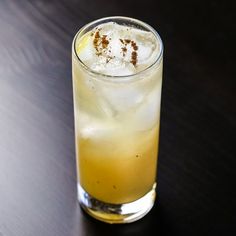 a tall glass filled with ice sitting on top of a wooden table