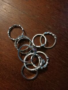 a bunch of silver rings sitting on top of a wooden table