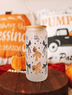 a glass cup with a straw in it sitting on a table next to pumpkins