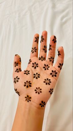 a woman's hand with black flowers painted on it