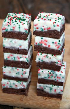 brownies with white frosting and sprinkles on a wooden cutting board