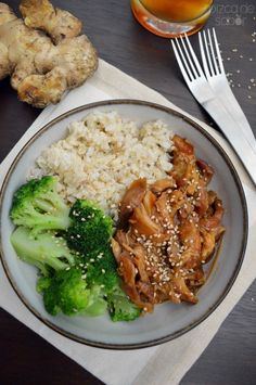 a plate with rice, broccoli and chicken on it next to a glass of beer