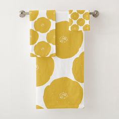 two yellow and white towels hanging on a towel rack next to a toilet paper roll