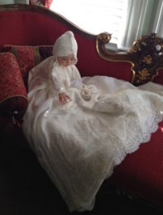 a small child in a white dress sitting on a red couch