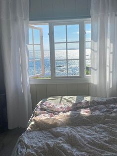 a bed sitting under a window next to a white curtain