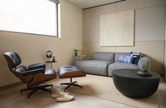 a living room with a couch, chair and ottoman next to a round coffee table