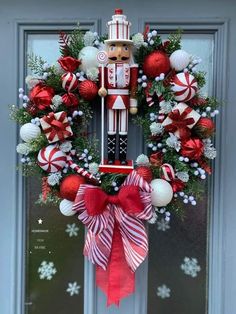 a christmas wreath with a nutcracker and candy canes hanging on the front door