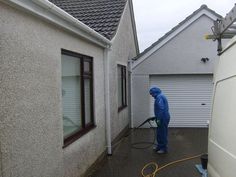 a man in blue coveralls is using a pressure washer on a driveway