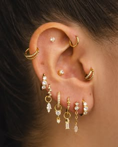 a woman's ear is adorned with gold and diamond earrings, which are dangling from the back of her ear