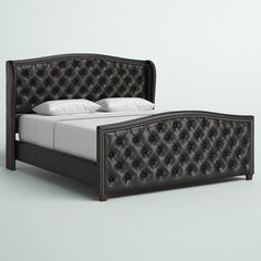 a bed with black leather headboard and foot board is shown in front of a gray background