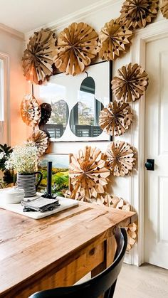 a wooden table topped with lots of paper flowers next to a white door and window