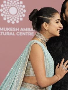 a man and woman standing next to each other in front of a pink wall with the words mukesh amba cultural centre on it