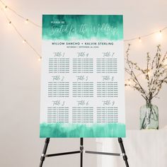 a purple and white wedding seating plan on a easel with lights in the background