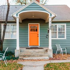 an orange door sits in front of a gray house