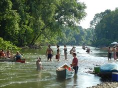 many people are wading in the river with canoes