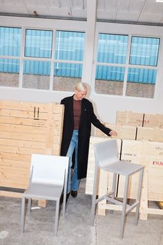 an older man standing next to some chairs in a room filled with wooden pallets