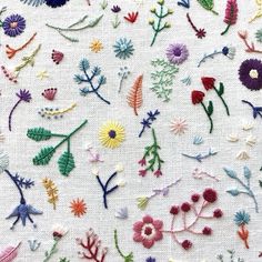 an embroidered fabric with various flowers and leaves on it's side, all in different colors