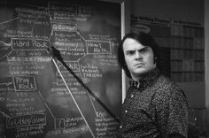 a man standing in front of a blackboard with writing on it and an arrow sticking out of it