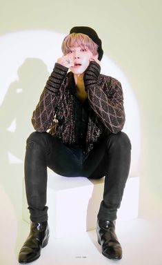 a young man sitting on top of a white chair with his hands to his face