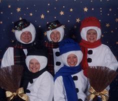 four women dressed in snowmen with brooms and scarves pose for a photo